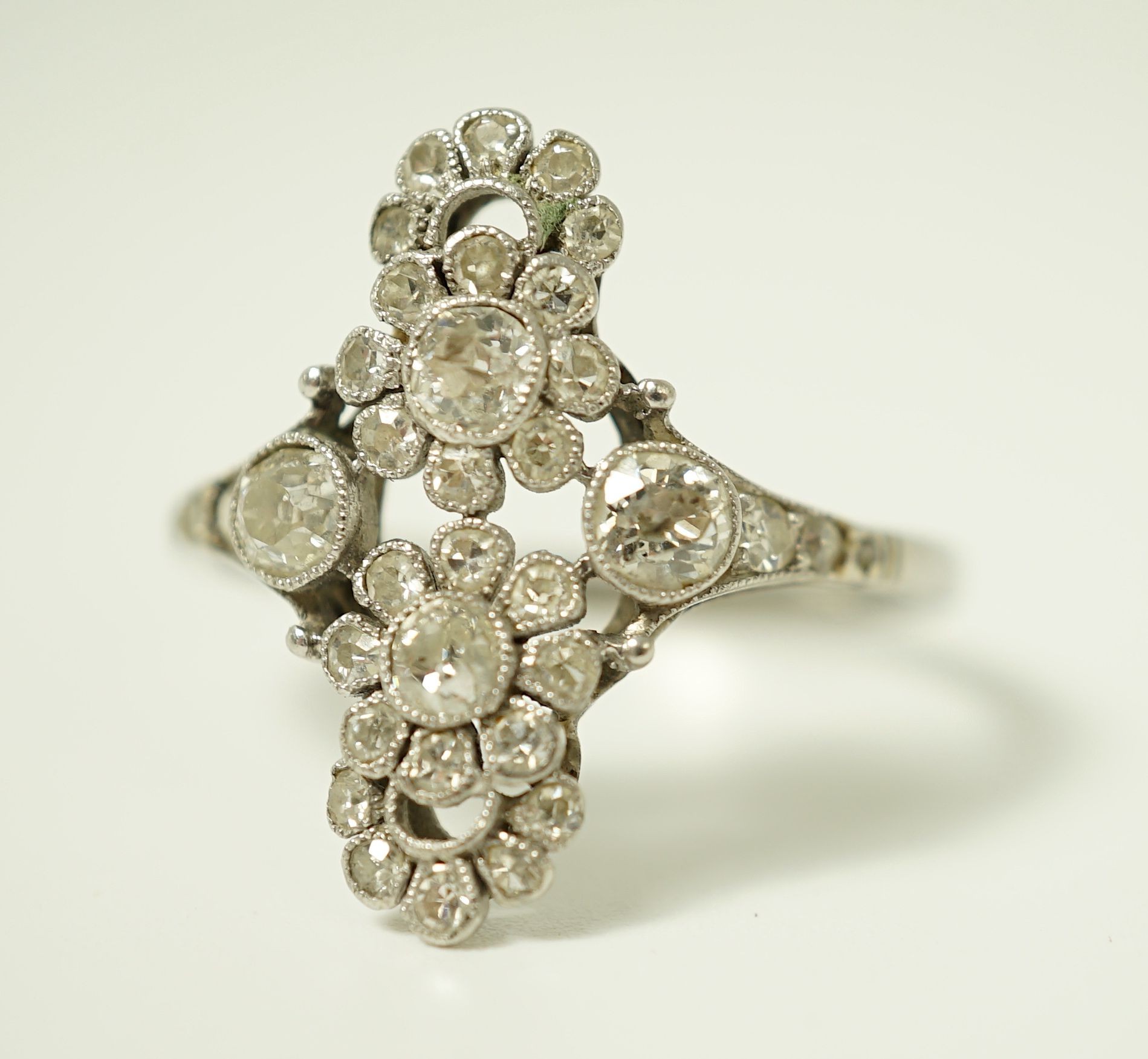 A 1920's platinum and millegrain diamond set flower head cluster upfinger ring